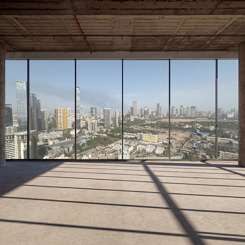 Interior view of a high-rise office floor with floor-to-ceiling glass windows overlooking a city skyline