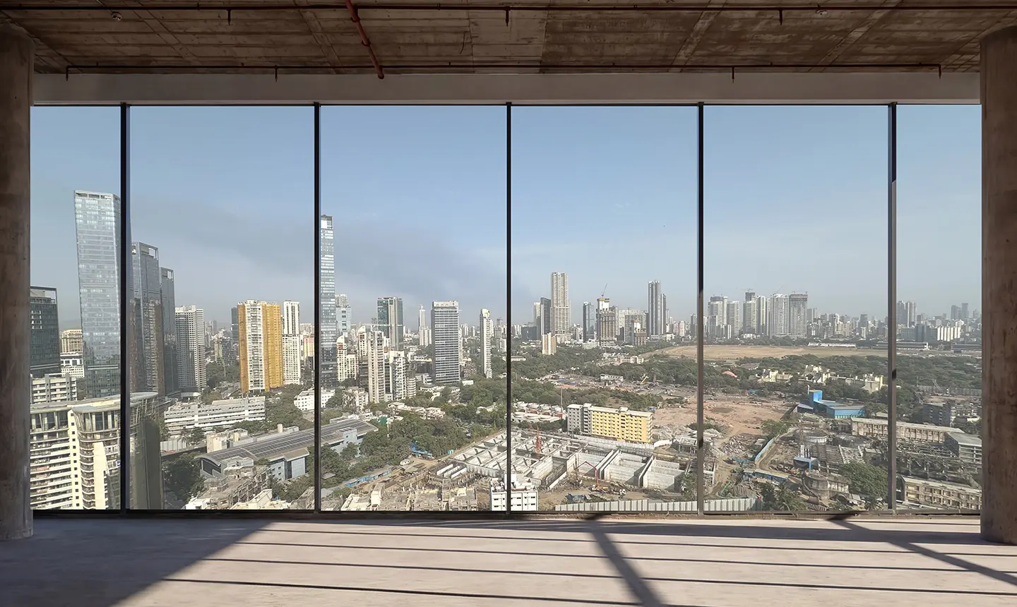 Interior view of a high-rise office floor with floor-to-ceiling glass windows overlooking a city skyline